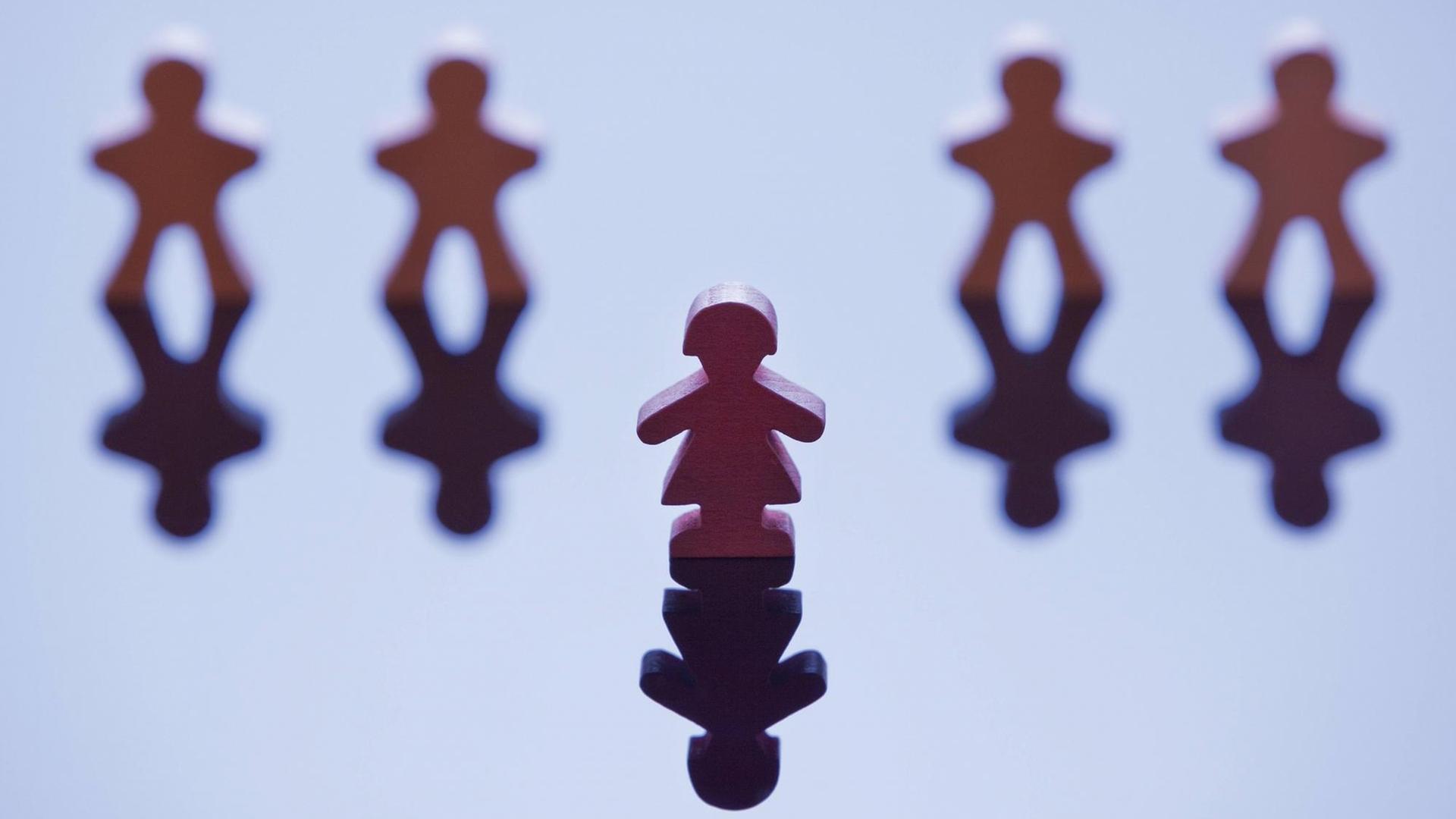 Vier männlich wirkende Spielfiguren stehen in einer Reihe mit einer Lücke in der Mitte, davor steht eine weiblich wirkende Figur. Vier männlich wirkende Spielfiguren stehen in einer Reihe mit einer Lücke in der Mitte, davor steht eine weiblich wirkende Figur.