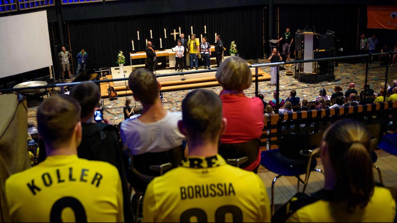 Fußballfans des Vereins Borussia Dortmund sitzen in der Kaiser-Wilhelm-Gedächtniskirche in Berlin während eines ökumenischen Gottesdienstes anlässlich des DFB-Pokalfinales der Männer im Rahmen des 36. Deutschen Evangelischen Kirchentages. Fußballfans des Vereins Borussia Dortmund sitzen in der Kaiser-Wilhelm-Gedächtniskirche in Berlin während eines ökumenischen Gottesdienstes anlässlich des DFB-Pokalfinales der Männer im Rahmen des 36. Deutschen Evangelischen Kirchentages.