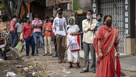 Menschen in Kalkutta stehen in einer Reihe und warten auf Essen, das von einer NGO ausgeteilt wird.