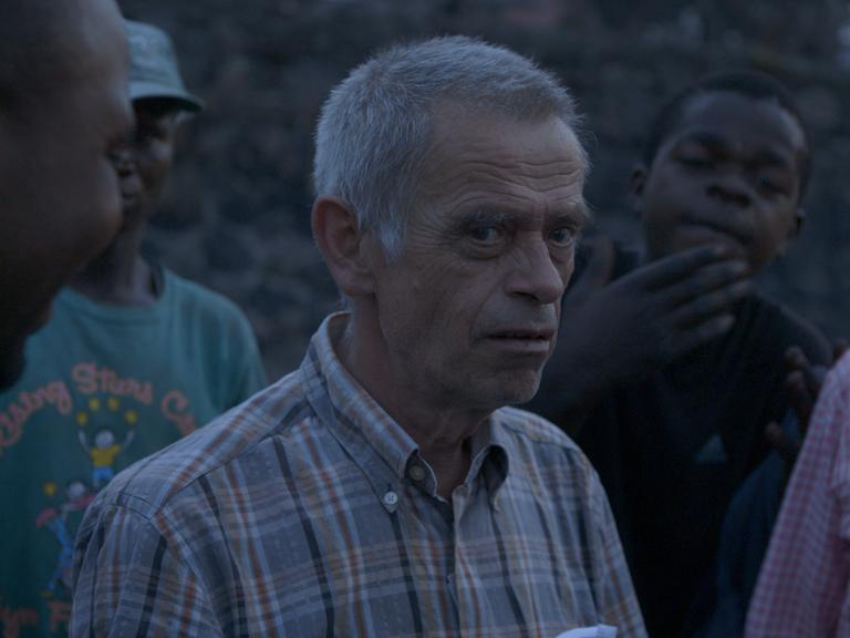 Eine Gruppe Männer aus dem Congo stehen in bläulichen Licht beisammen.