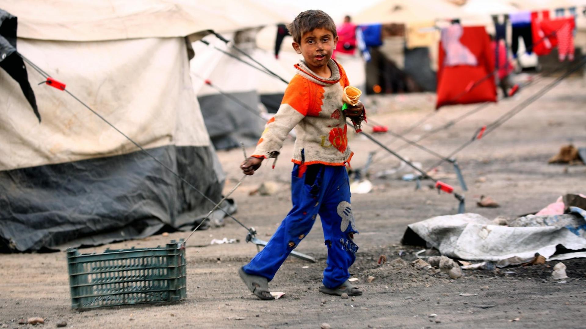 Ein syrisches Kind in einem Flüchtlingslager bei Raqqa zieht eine Kiste hinter sich her. Ein syrisches Kind in einem Flüchtlingslager bei Raqqa zieht eine Kiste hinter sich her.