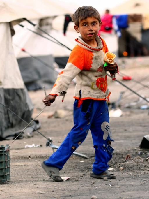 Ein syrisches Kind in einem Flüchtlingslager bei Raqqa zieht eine Kiste hinter sich her.