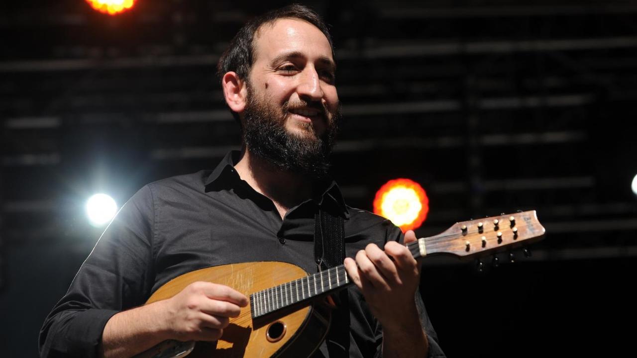 Ein Mann mit Ukulele steht auf einer Bühne. Ein Mann mit Ukulele steht auf einer Bühne.