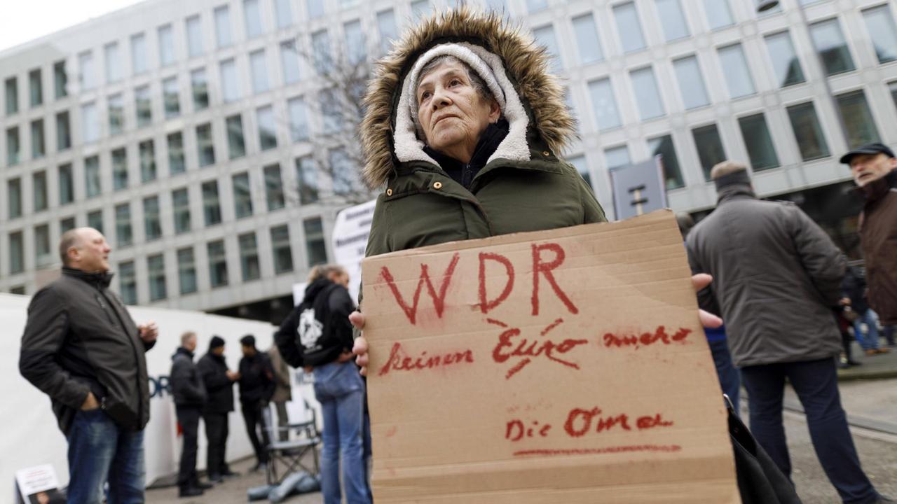 Eine Seniorin hält ein Plakat mit der Aufschrift: WDR - keinen Euro mehr. Die Oma.