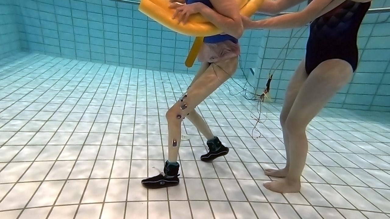 Eine junge Frau geht geführt durch ein hüfthohes Schwimmbecken. Eine junge Frau geht geführt durch ein hüfthohes Schwimmbecken.