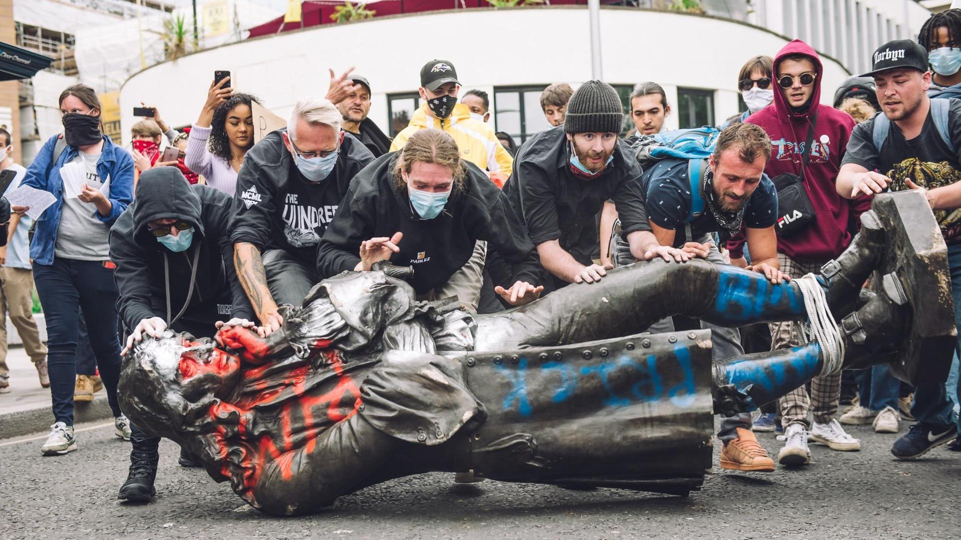 Protestierende rollen eine massive Statue über die Straßen von Bristol. Diese hatten sie zuvor demontiert. Protestierende rollen eine massive Statue über die Straßen von Bristol. Diese hatten sie zuvor demontiert.