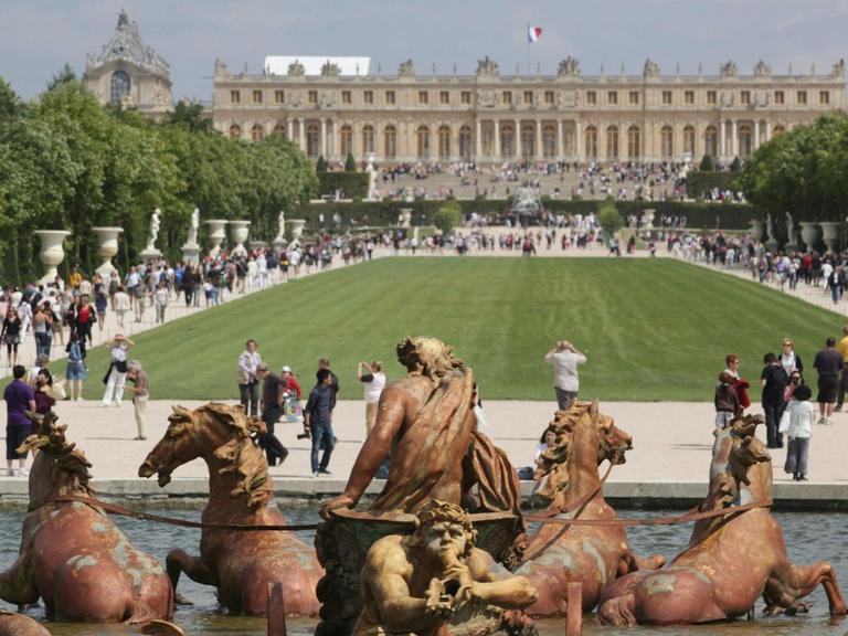 Das Bild zeigt die Gartenfassade des Schlosses von Versailles, im Vordergrund der Apollo-Brunnen.