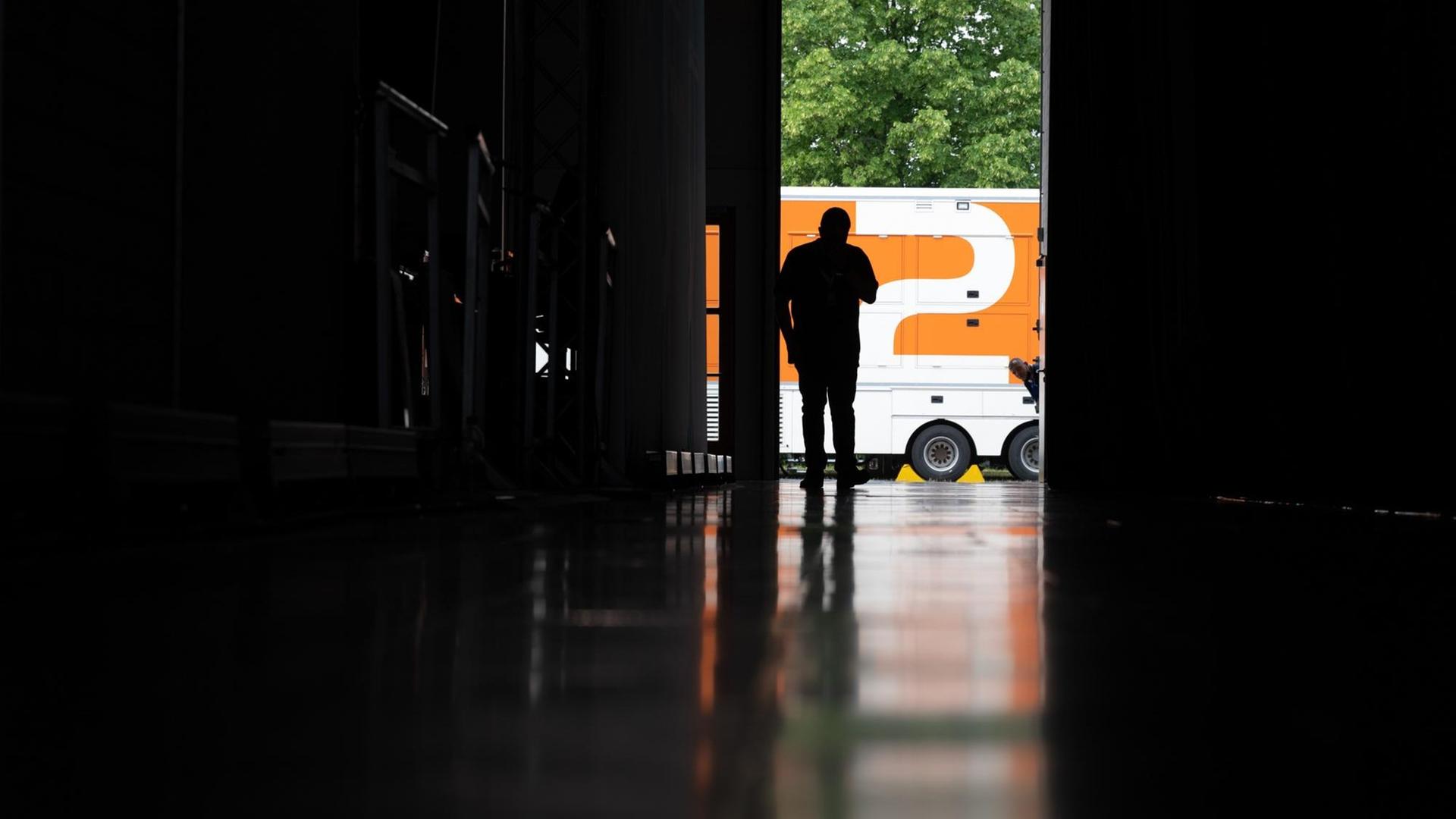 Ein Mann zeichnet sich auf dem Messegelände in einer Messehalle vor einem Übertragungswagen des ZDF als Silhouette ab Ein Mann zeichnet sich auf dem Messegelände in einer Messehalle vor einem Übertragungswagen des ZDF als Silhouette ab