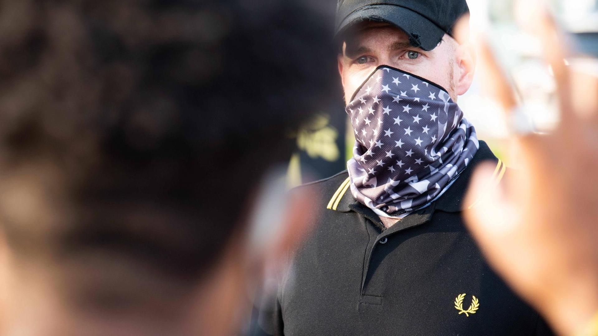 Ein vermummter Mann mit "Proud Boys"-Mütze und Fred Perry-Shirt mit goldenem Lorbeerkranz. Ein vermummter Mann mit "Proud Boys"-Mütze und Fred Perry-Shirt mit goldenem Lorbeerkranz.