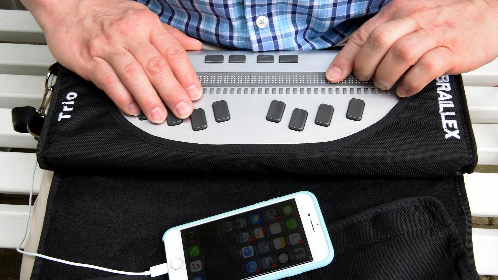 Mit einer Braillezeile und einem Smartphone, mit Kopfhörern verbunden, arbeitet Thomas Kahlisch, Präsidiumsmitglied des Deutschen Blinden- und Sehbehindertenverbandes (DBSV), am 30.05.2017 in Hannover (Niedersachsen). Mit einer Braillezeile und einem Smartphone, mit Kopfhörern verbunden, arbeitet Thomas Kahlisch, Präsidiumsmitglied des Deutschen Blinden- und Sehbehindertenverbandes (DBSV), am 30.05.2017 in Hannover (Niedersachsen).