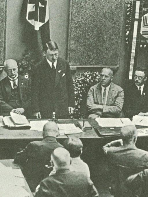 Adolf Hitler bei einem Parteitag der NSDAP 1925 in München, links von ihm Alfred Rosenberg, rechts Georg Strasser und Heinrich Himmler