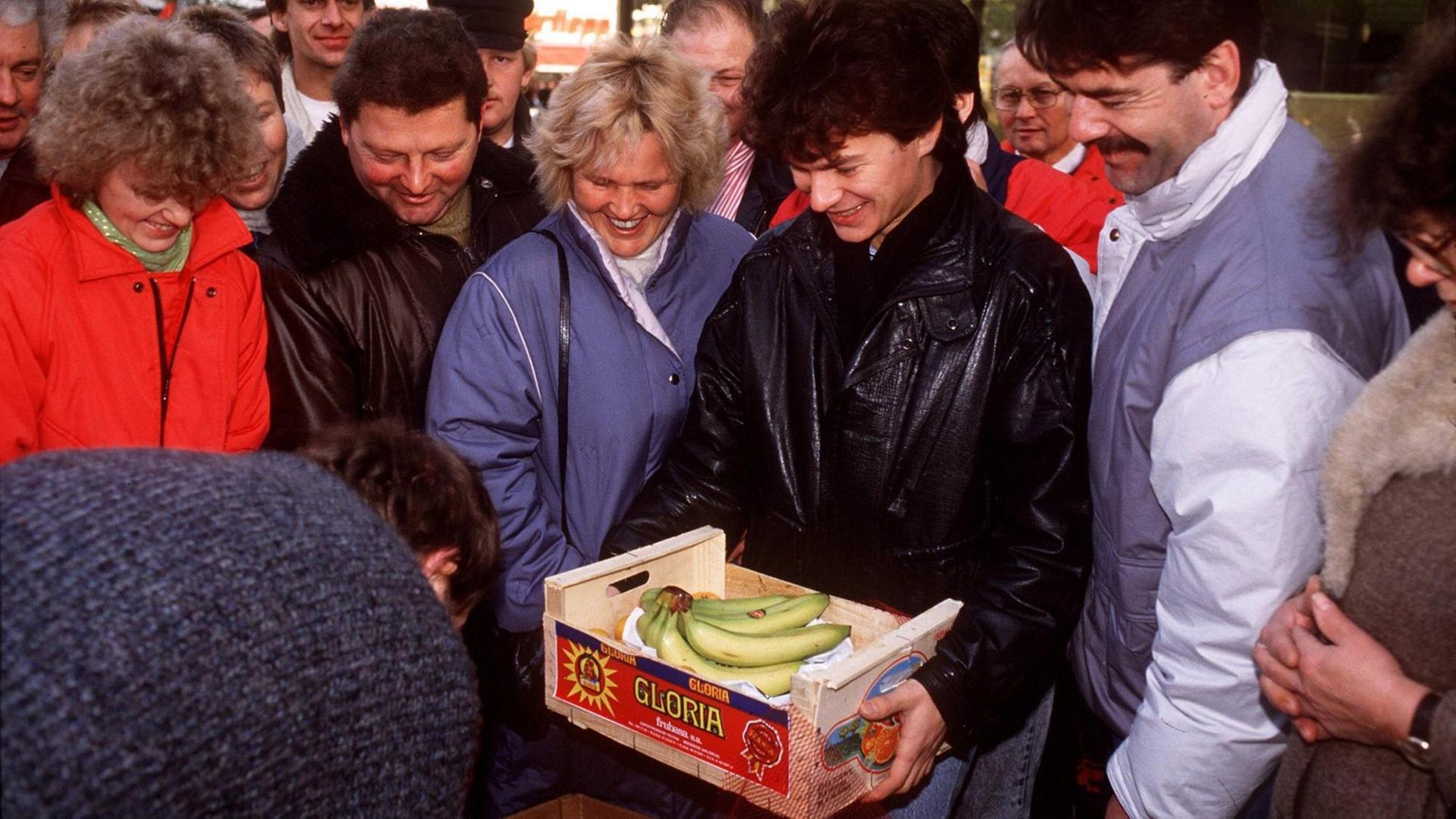 Am Tag nach der Maueröffnung nutzen einige DDR-Bürger ihr Begrüßungsgeld zum Einkauf von Bananen, die in der DDR sehr teuer waren.