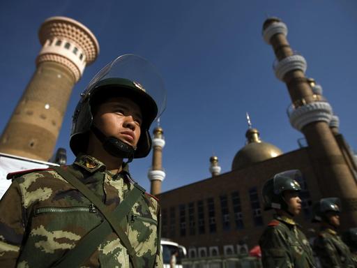 Aus einer Untersicht sind uniformierte und bewaffnete Sicherheitskräfte zu sehen, die vor einer Mosche patrouillieren.