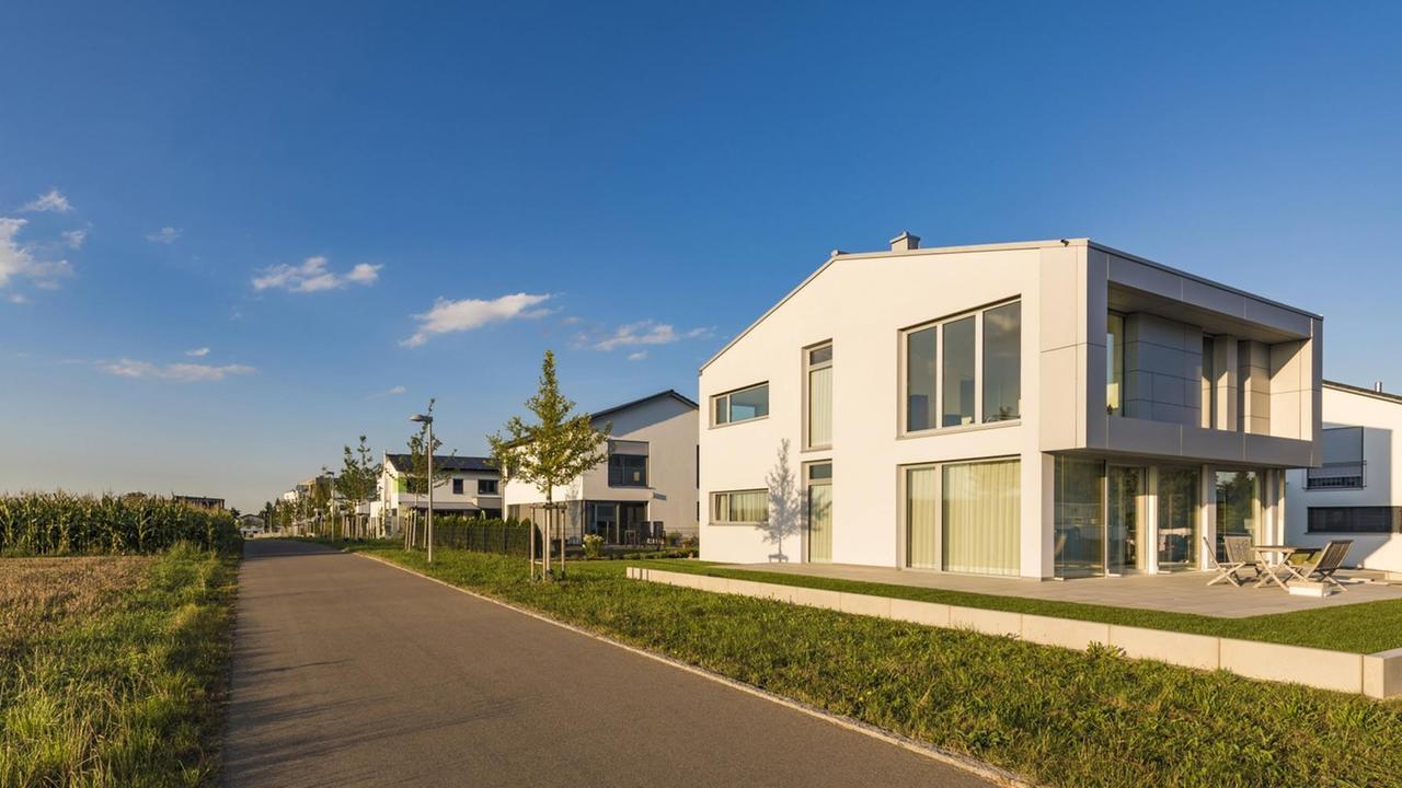 Neu gebaute Häuser in weißer Farbe stehen im Dezember 2019 entlang einer Straße in Ulm in Baden-Württemberg, gegenüber Felder, darüber blauer Himmel. Neu gebaute Häuser in weißer Farbe stehen im Dezember 2019 entlang einer Straße in Ulm in Baden-Württemberg, gegenüber Felder, darüber blauer Himmel.
