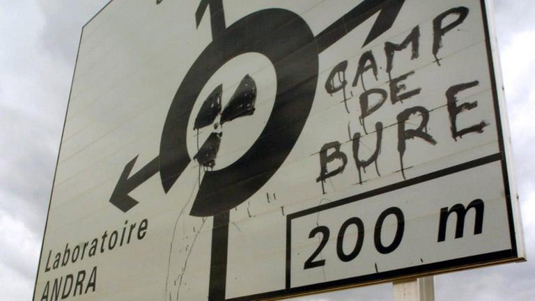 Ein Verkehrsschild, das mit einem Atomkraftzeichen und dem Hinweis auf "Camp De Bure" übermalt wurde Ein Verkehrsschild, das mit einem Atomkraftzeichen und dem Hinweis auf "Camp De Bure" übermalt wurde