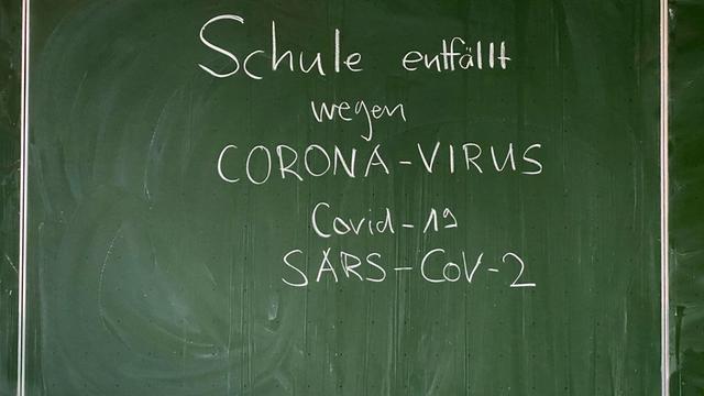 Auf einer Tafel steht geschrieben: Schule entfällt wegen Corona-Virus, Covid-19, SARS-CoV-2