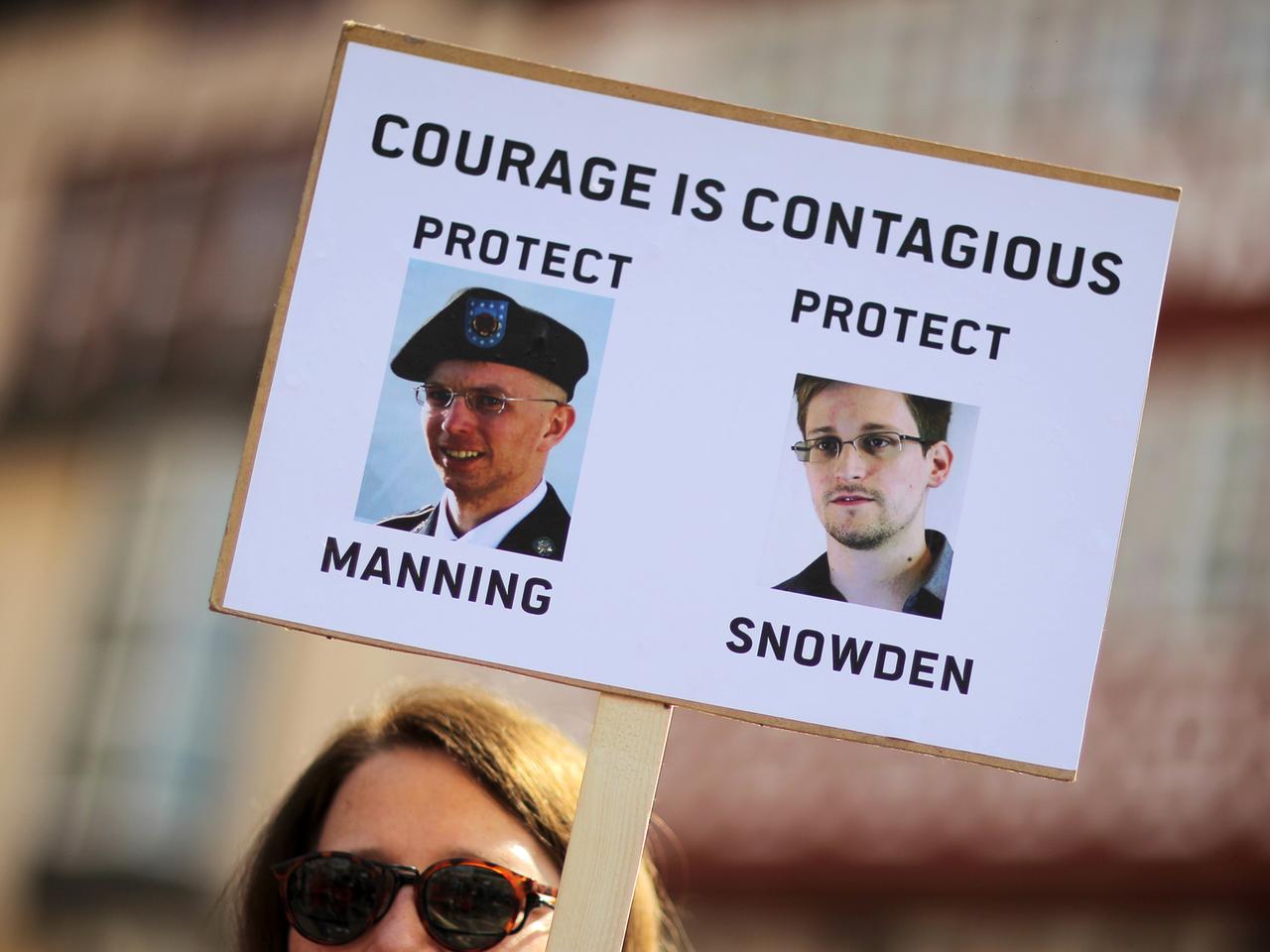 Eine Frau demonstriert in Frankfurt am Main und hält dabei ein Schild hoch, auf dem die Abbilder von Edward Snowden (r) und Bradley Manning zu sehen sind, da drüber die Aufschrift "courage ist contagious" (zu Deutsch: Courage ist ansteckend). Eine Frau demonstriert in Frankfurt am Main und hält dabei ein Schild hoch, auf dem die Abbilder von Edward Snowden (r) und Bradley Manning zu sehen sind, da drüber die Aufschrift "courage ist contagious" (zu Deutsch: Courage ist ansteckend).