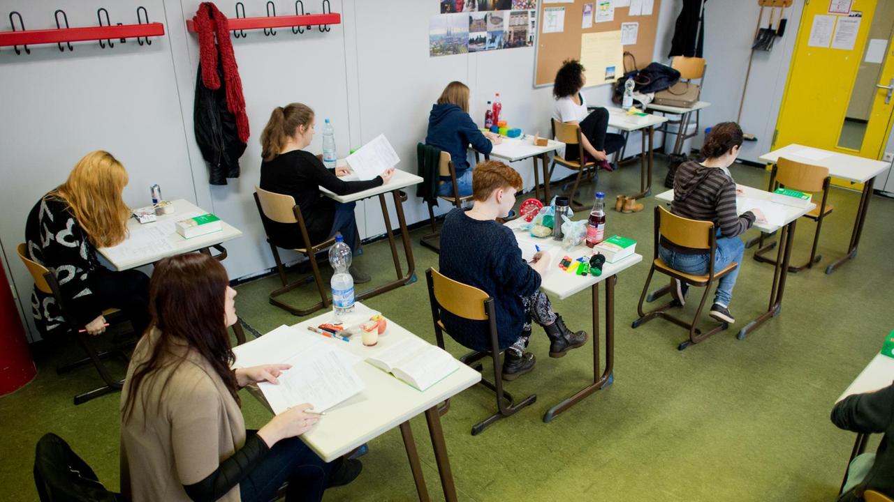 Die Schüler sitzen an einzeln aufgestellten Tischen und arbeiten an ihren Aufgaben. Die Schüler sitzen an einzeln aufgestellten Tischen und arbeiten an ihren Aufgaben.