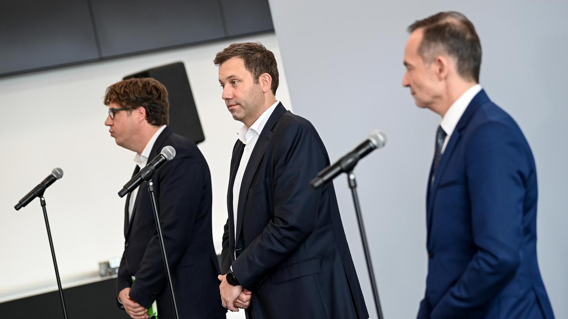 Michael Kellner, Lars Klingbeil und Volker Wissing stehen gemeinsam vor Mikrofonen . Vor der Seite fotografiert blicken sie in die Richtung der Pressevertreter.