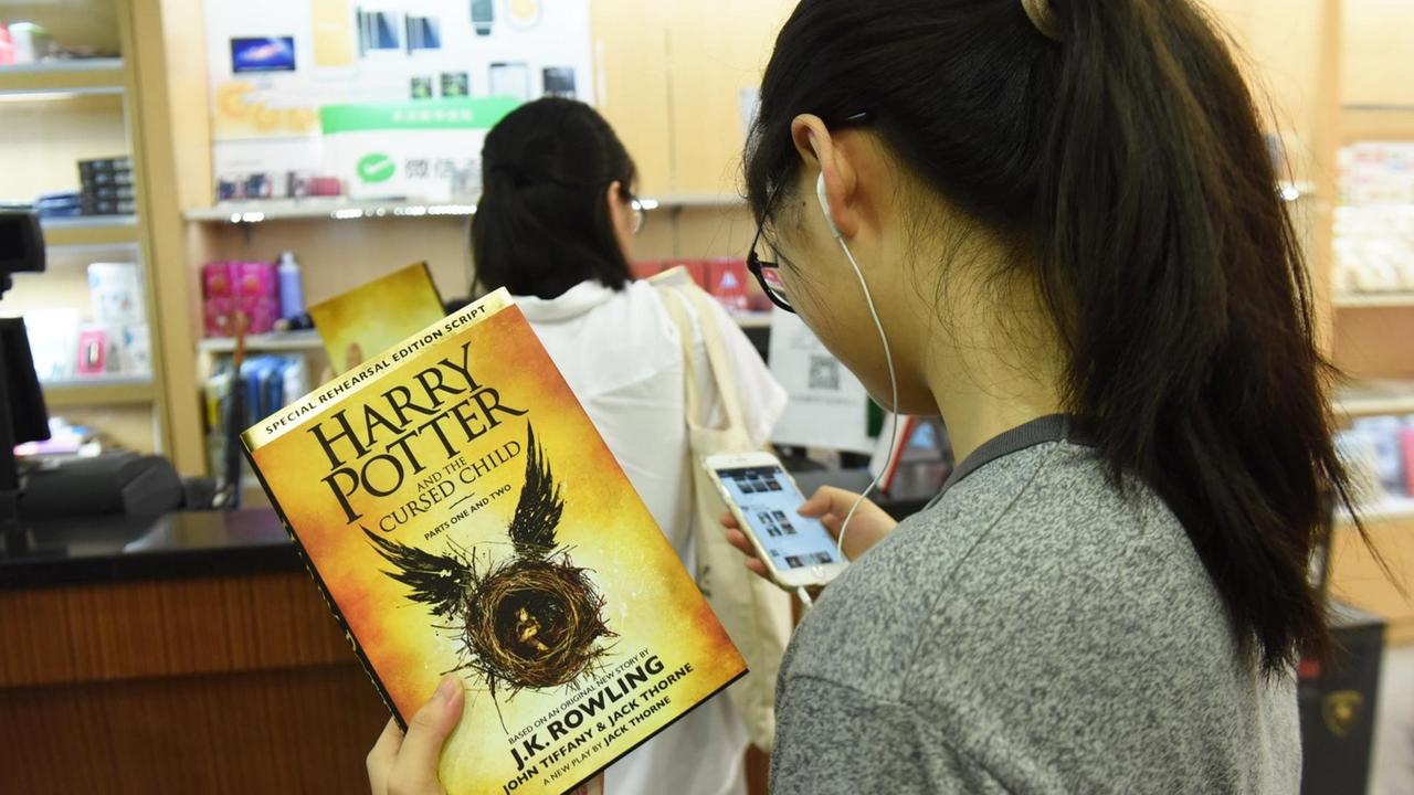 Sie sehen eine junge Frau mit einem Potter-Buch in der Hand. Sie sehen eine junge Frau mit einem Potter-Buch in der Hand.