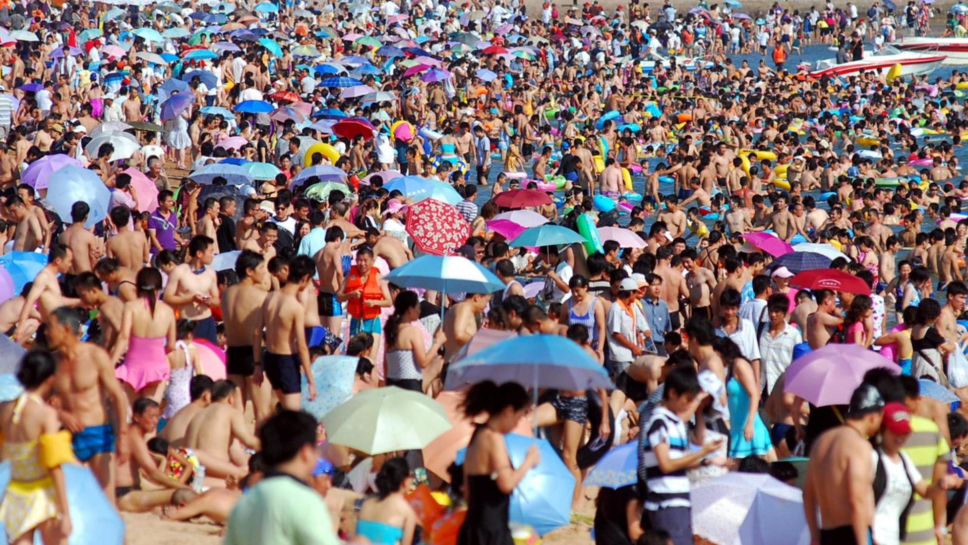 Sehr viele Menschen drängen sich am Strand in der Bucht bei Qingdao (China). Sehr viele Menschen drängen sich am Strand in der Bucht bei Qingdao (China).