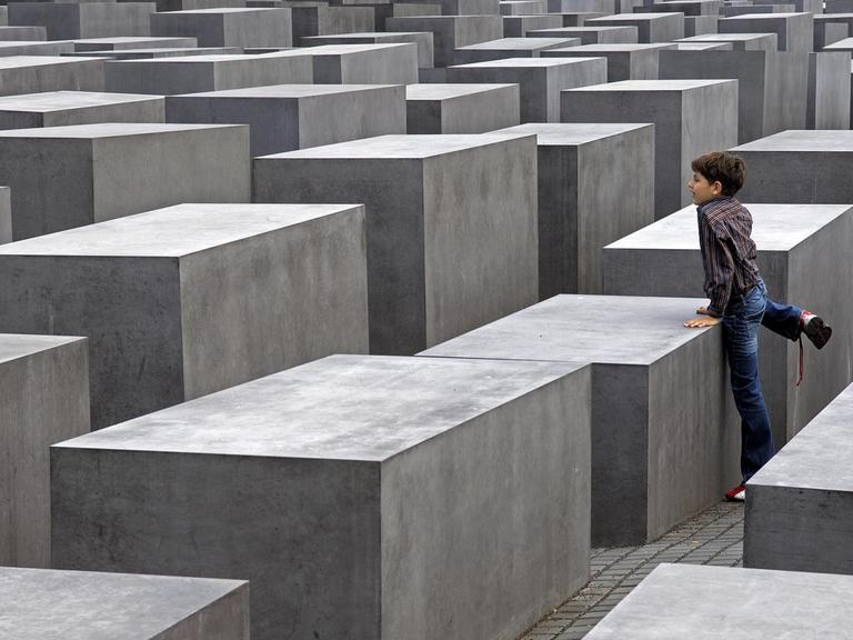 Ein kleiner Junge klettert am Holocaustmahnmal in Berlin.