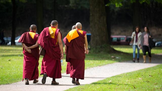 Buddhistische Mönche gehen am 22.08.2014 in Hamburg nach der Ankunft des Dalai Lama, dem geistlichen Oberhaupt der Tibeter, auf einem Fußweg zum CCH.
