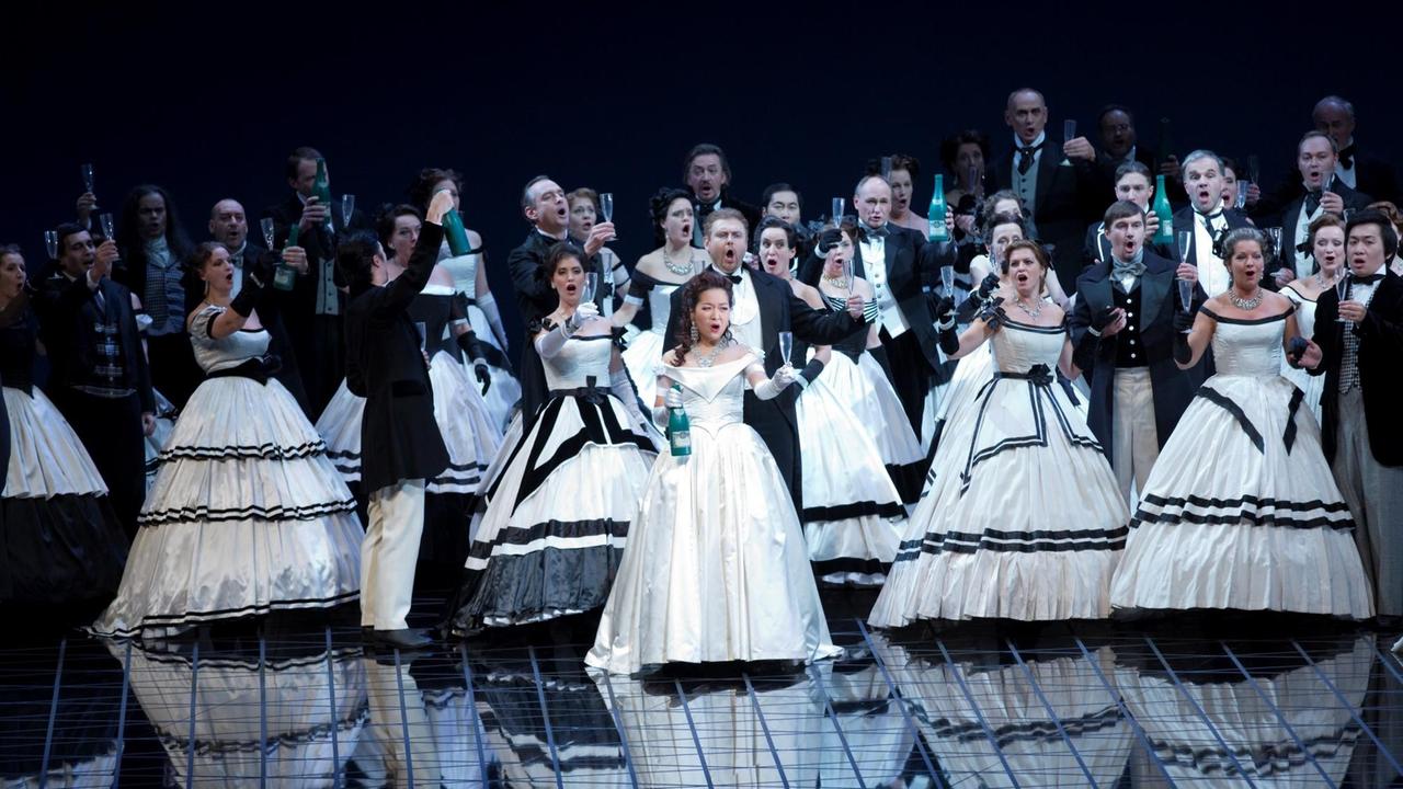 Der Chor steht in Ballkleidung auf der Bühne für eine Festszene. Der Chor steht in Ballkleidung auf der Bühne für eine Festszene.