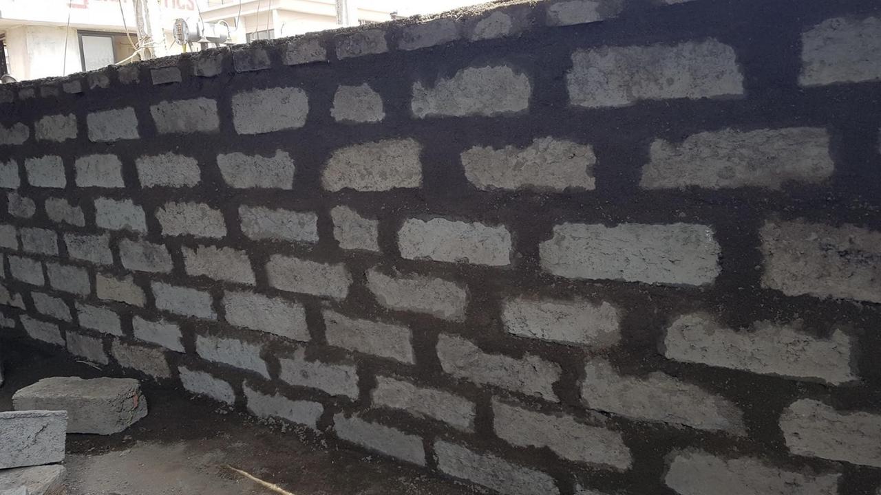 Eine frisch gebaute Mauer aus ziegelförmigen, grauen Bausteinen