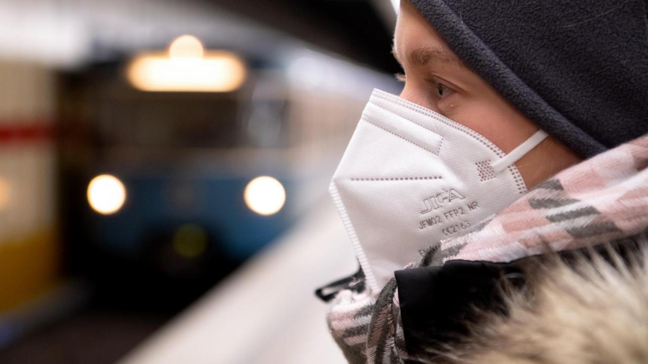 Ein Frau mit FFP2-Maske wartet in einer U-Bahnstation auf die Bahn. Ein Frau mit FFP2-Maske wartet in einer U-Bahnstation auf die Bahn.