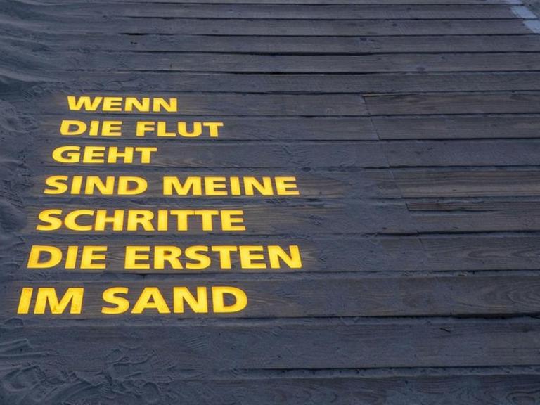 Eine Lichtinstallation von Jan Philip Scheibe mit einem Gedicht auf der Insel Langeoog: "Wenn die Flut geht, sind meine Schritte die ersten im Sand".