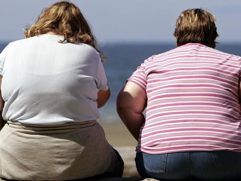 Zwei übergewichtige Menschen am Strand.