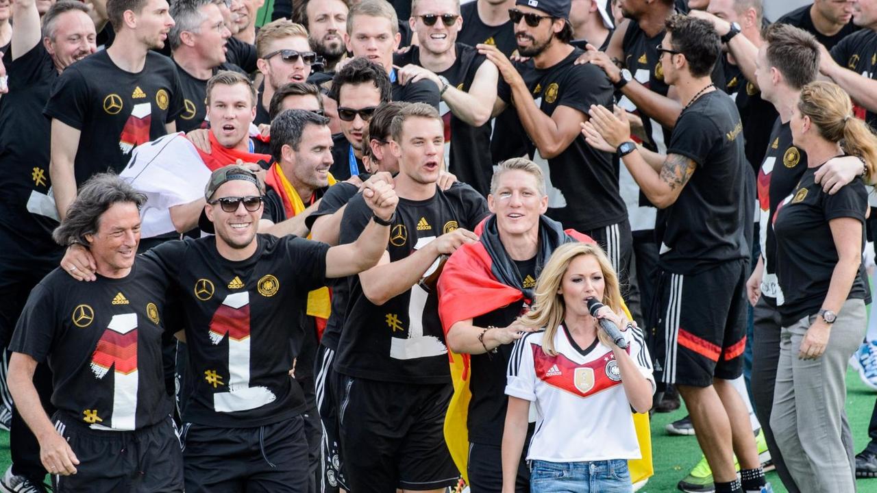 Die Sängerin Helene Fischer und die Spieler der Fussball Nationalmannschaft feiern am 15.07.2014 beim Empfang an der Fanmeile am Brandenburger Tor in Berlin.