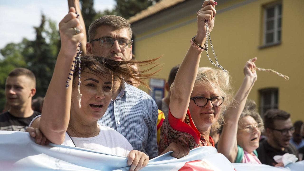 Demonstranten halten Rosenkränze in die Höhe. Demonstranten halten Rosenkränze in die Höhe.