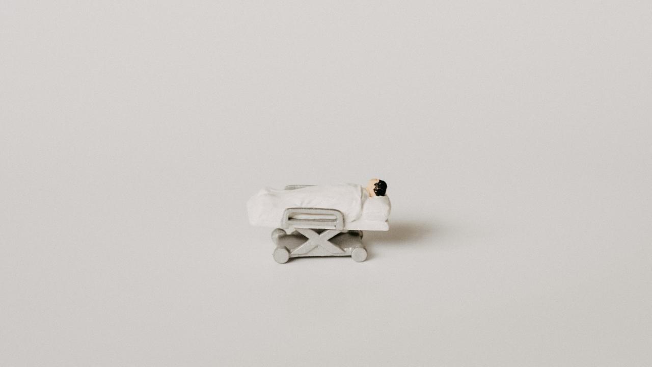 Miniaturfigur einer bettlägerigen Person Miniaturfigur einer bettlägerigen Person