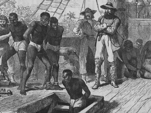 Eine historische Illustration um 1835 zeigt Sklaven an Bord eines Sklavenschiffes, die gefesselt werden, bevor sie in den Laderaum gebracht werden.