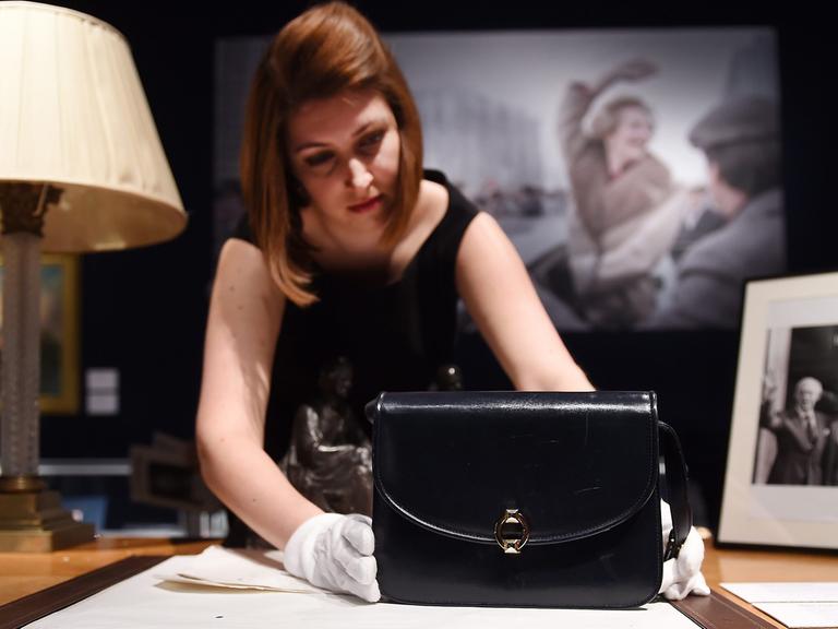 Eine Mitarbeiterin von Christie's präsentiert eine Handtasche von Margaret Thatcher. Über 400 Objekte aus dem Nachlass der britischen Premierministerin werden im Auktionshaus versteigert.
