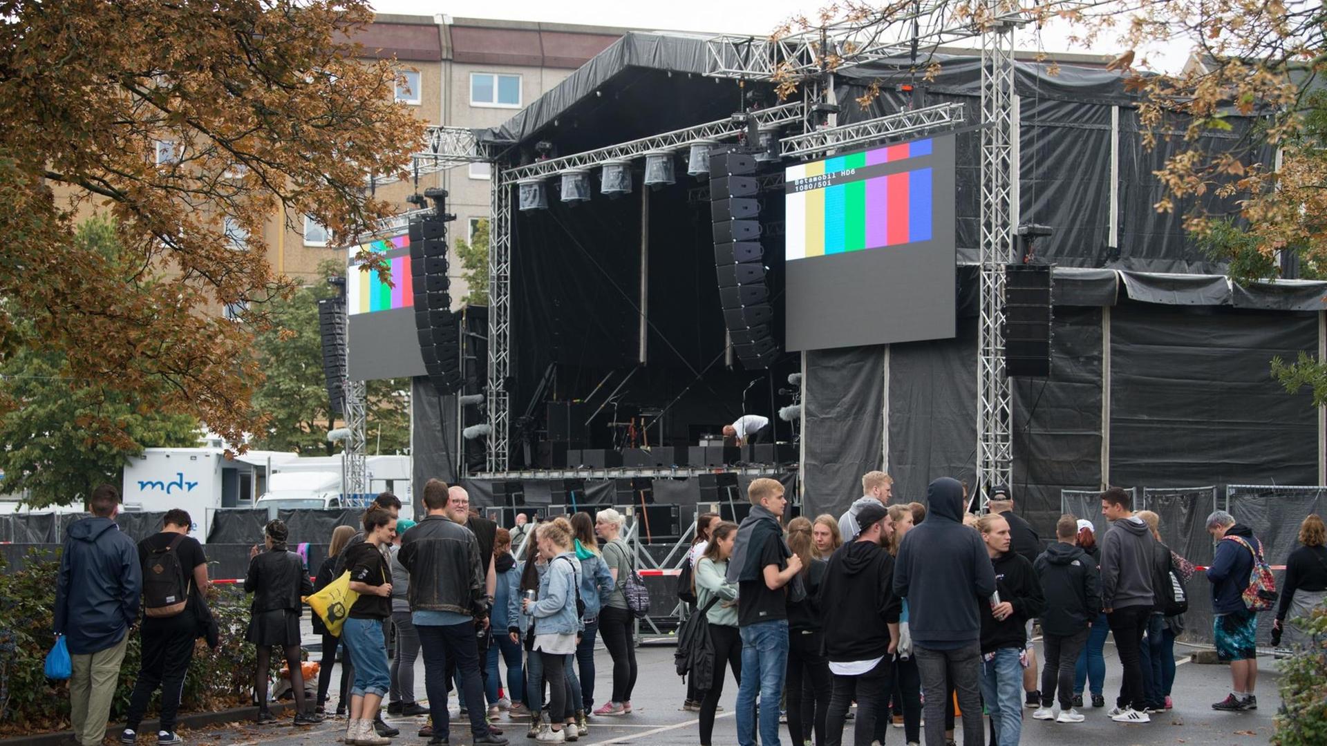 03.09.2018, Sachsen, Chemnitz: Konzertbesucher warten auf dem Parkplatz an der Johanniskirche hinter einer Absperrung vor der Bühne auf den Beginn des Konzerts.