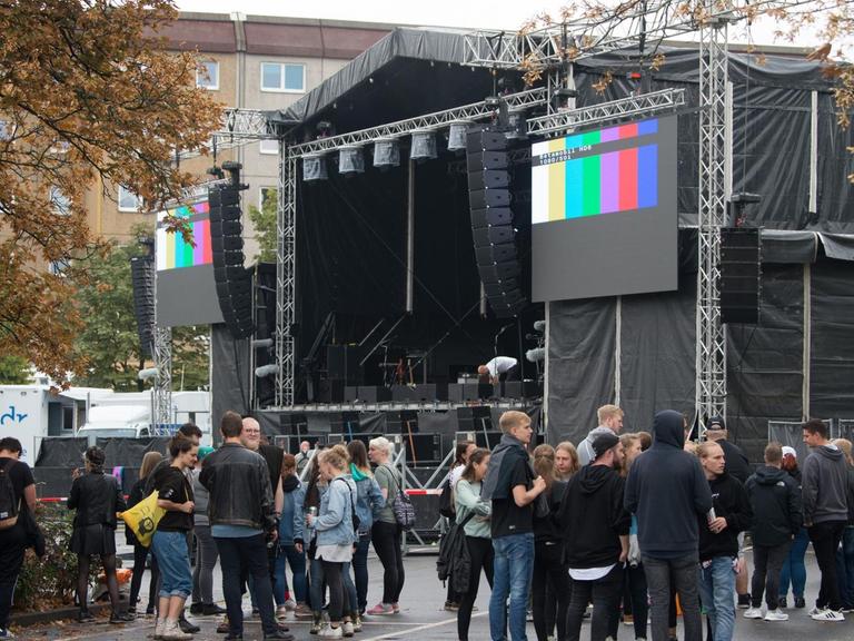 03.09.2018, Sachsen, Chemnitz: Konzertbesucher warten auf dem Parkplatz an der Johanniskirche hinter einer Absperrung vor der Bühne auf den Beginn des Konzerts.