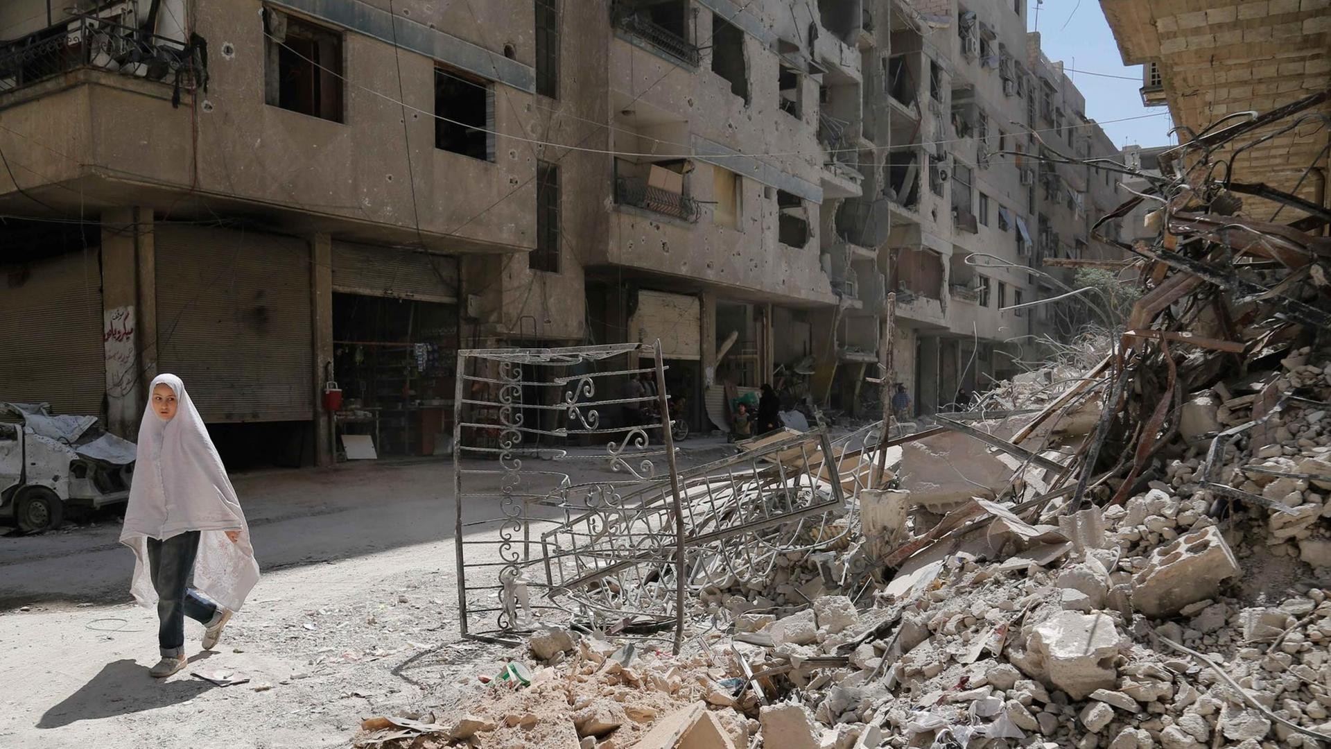 in Mädchen geht durch eine zerstörte Straße in der Stadt Ayn Tarma in der Region Ghouta östlich von Damaskus in Mädchen geht durch eine zerstörte Straße in der Stadt Ayn Tarma in der Region Ghouta östlich von Damaskus