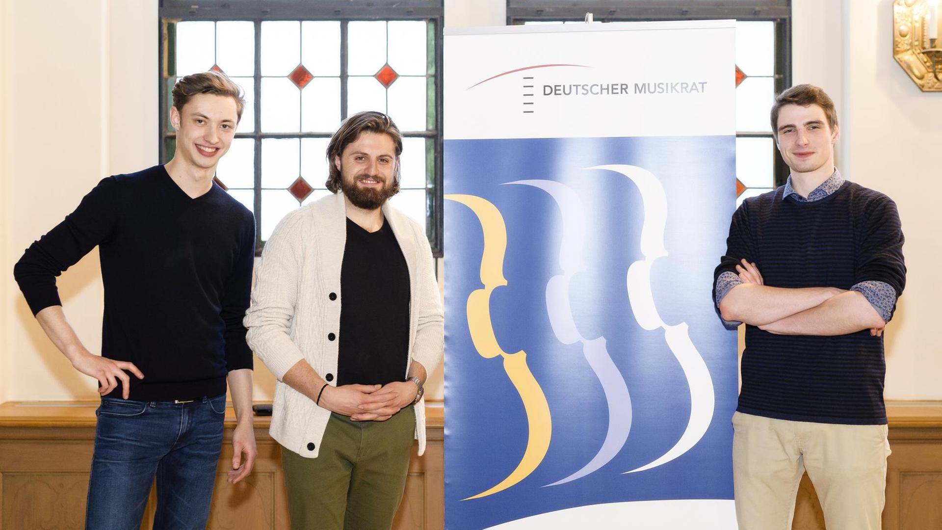 Drei Preisträger vor dem Banner des DMW Drei Preisträger vor dem Banner des DMW