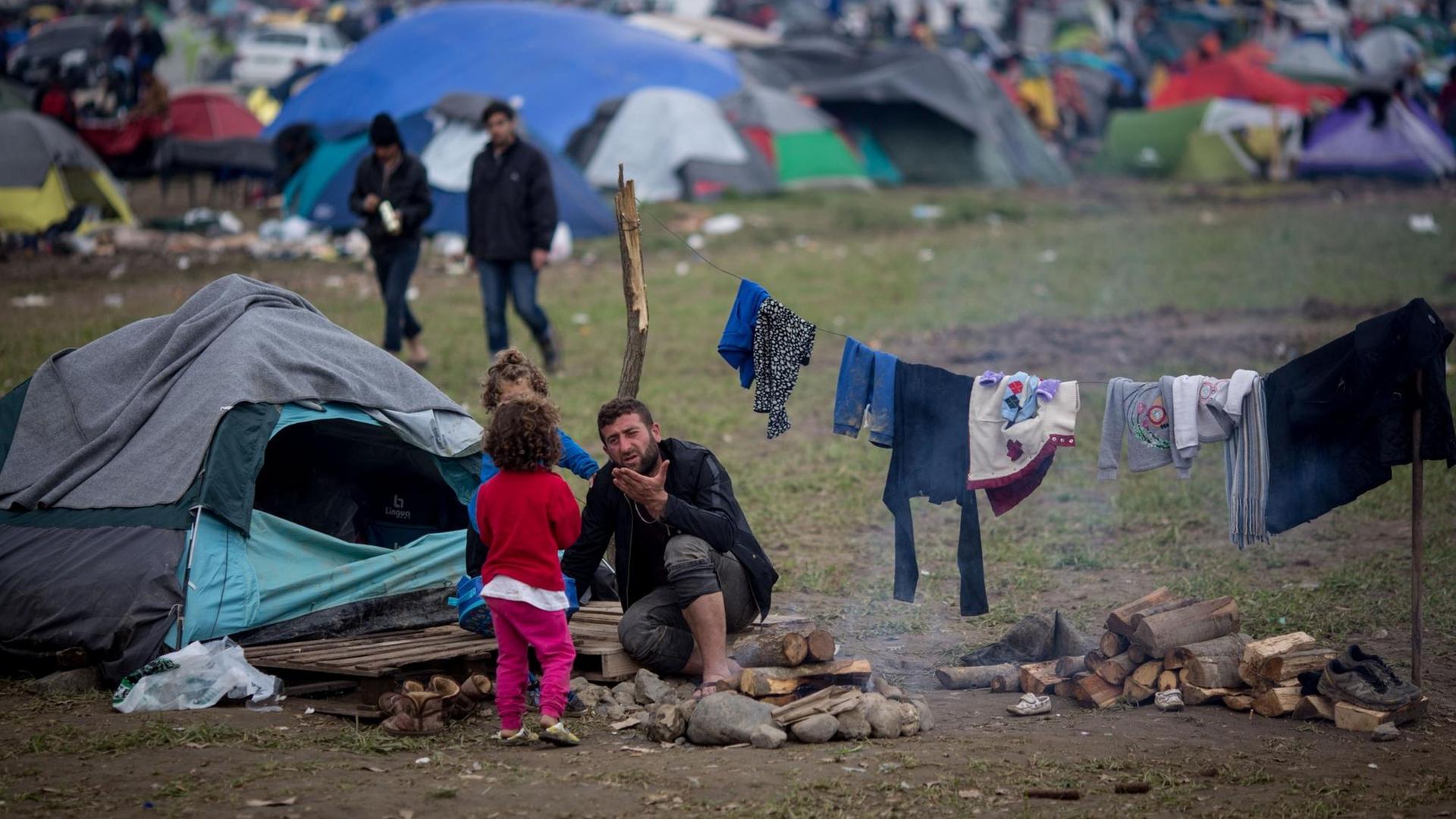 Ein Mann mit zwei Kindern sitzt am 11.03.2016 vor seinem Zelt im Flüchtlingslager in Idomeni an der Grenze zwischen Griechenland und Mazedonien. Ein Mann mit zwei Kindern sitzt am 11.03.2016 vor seinem Zelt im Flüchtlingslager in Idomeni an der Grenze zwischen Griechenland und Mazedonien.
