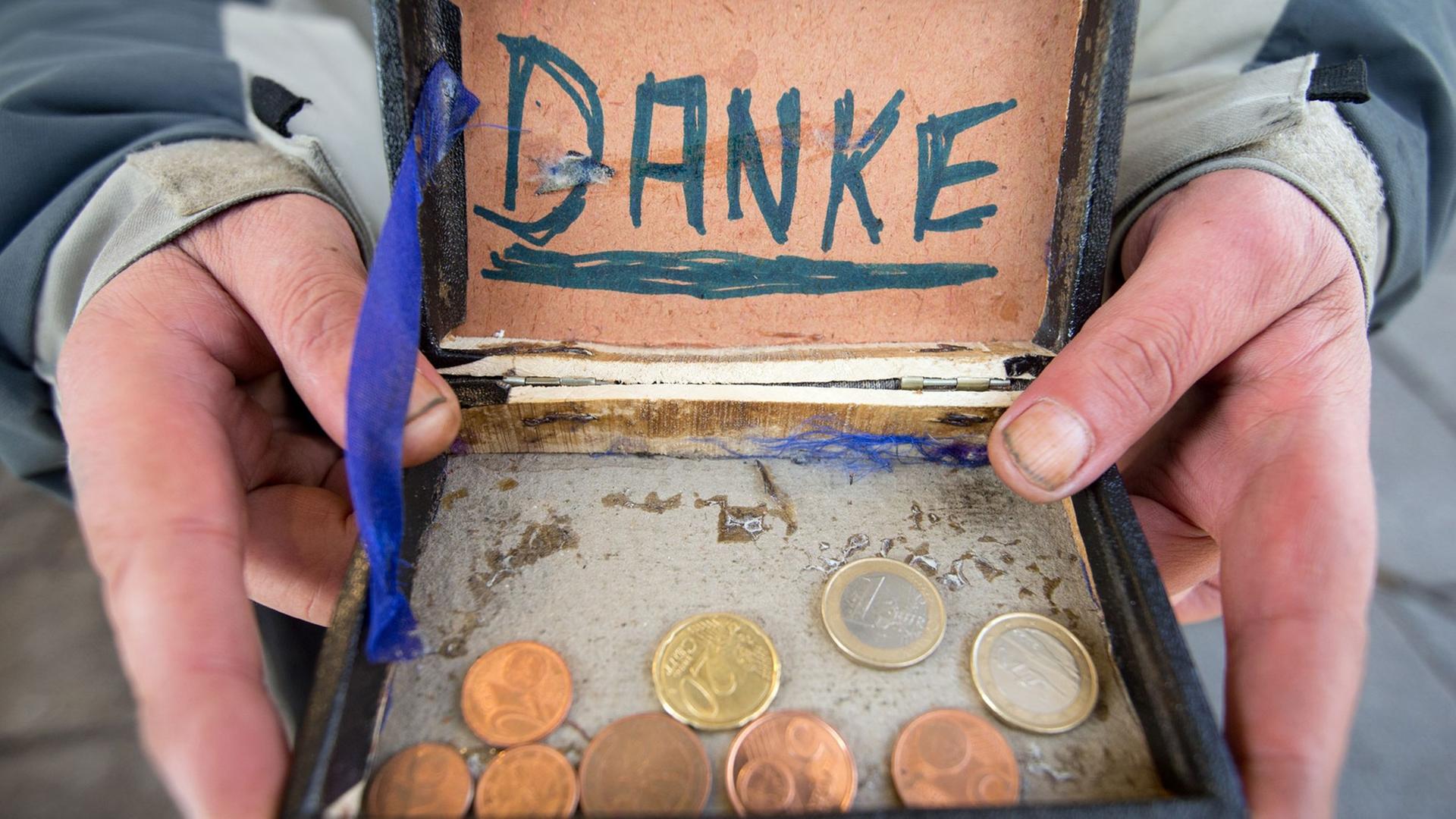 Ein Bettler hält eine alte Zigarrenkiste für Geldspenden in der Hand. Ein Bettler hält eine alte Zigarrenkiste für Geldspenden in der Hand.