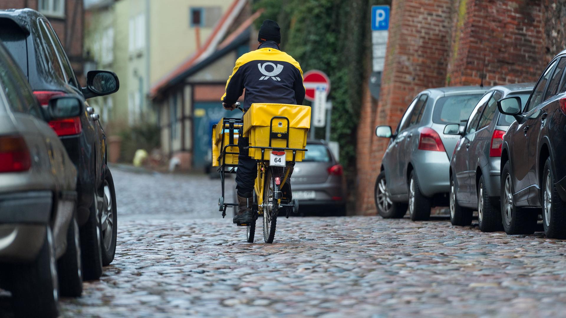Lüneburg: Ein Briefträger der Deutschen Post fährt mit dem Fahrrad durch die Innenstadt