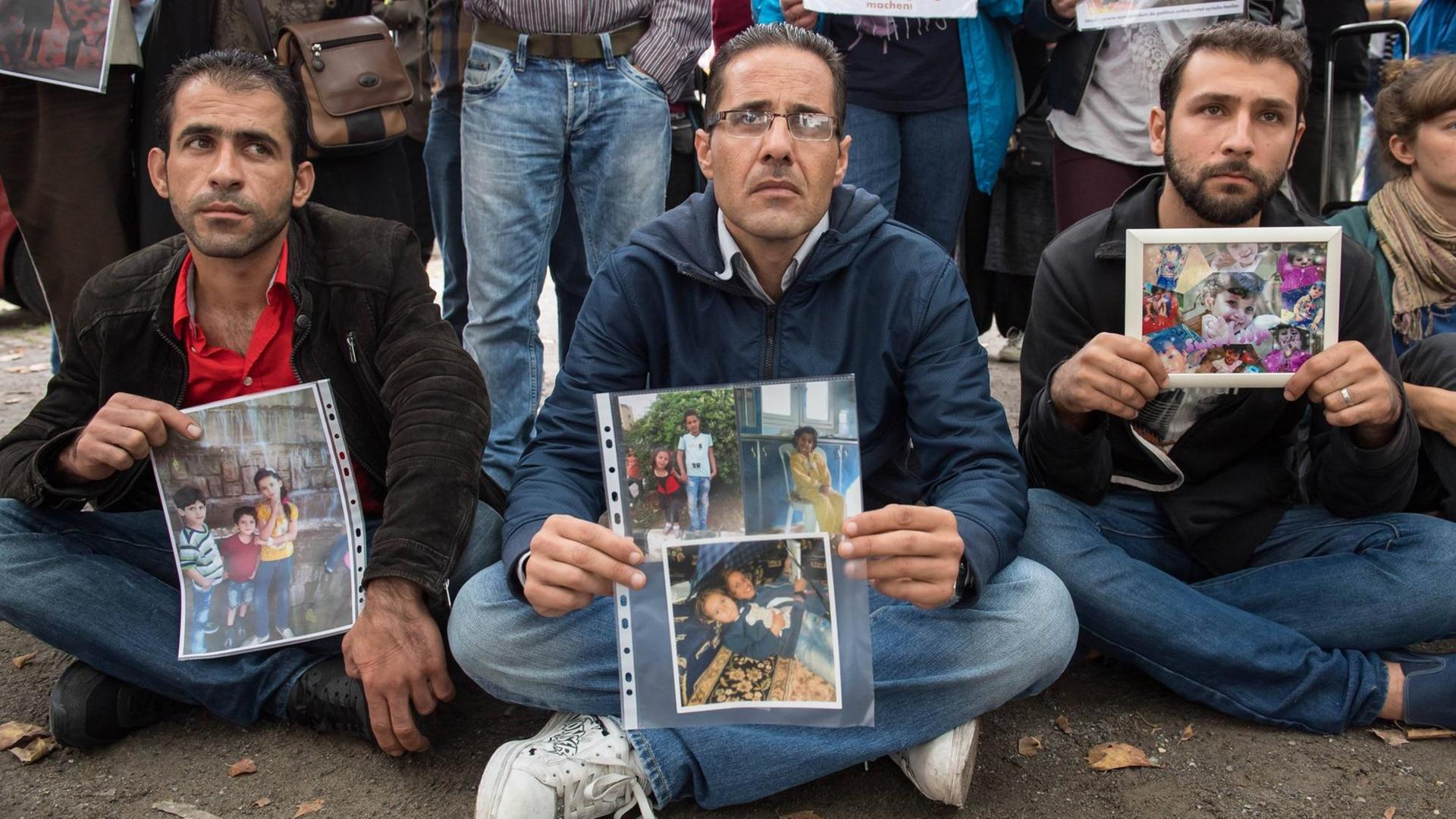 Mahnwache der Flüchtlingsinitiative "People meet People - Respekt e.V." vor dem Auswärtigen Amt in Berlin am 03. August 2016. Drei Männer sitzen am boden und halten Fotos ihrer Familienangehörigen. Mahnwache der Flüchtlingsinitiative "People meet People - Respekt e.V." vor dem Auswärtigen Amt in Berlin am 03. August 2016. Drei Männer sitzen am boden und halten Fotos ihrer Familienangehörigen.