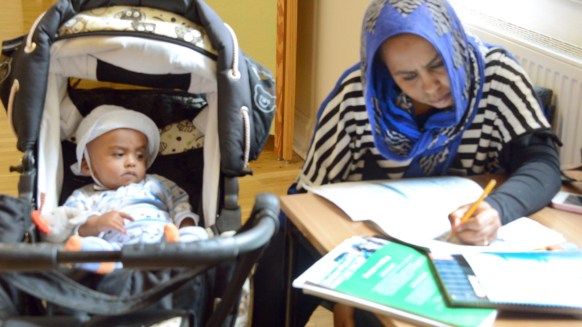 In der Volkshochschule in Leipzig sitzt eine Frau aus dem Sudan während einer Pause mit ihrem Kind an einem Fenster und lernt Deutsch.