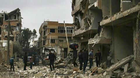 Das von der regierungskritischen Aktivistengruppe Ghouta Media Center (GMC) zur Verfügung gestellte Foto und durch Abgleich mit AP-Berichterstattung authentifizierte Foto zeigt Syrer, die Gebäude inspizieren, die durch einen Angriff der syrischen Luftwaffe zerstört wurden.