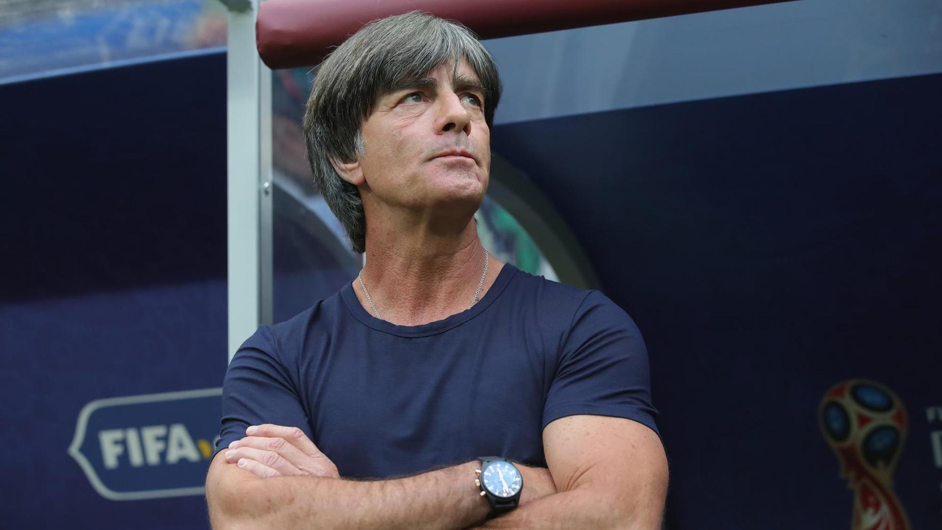 Joachim Löw steht vor einer Auswechselbank, er hat die Arme verschränkt und schaut in die Ferne. Joachim Löw steht vor einer Auswechselbank, er hat die Arme verschränkt und schaut in die Ferne.