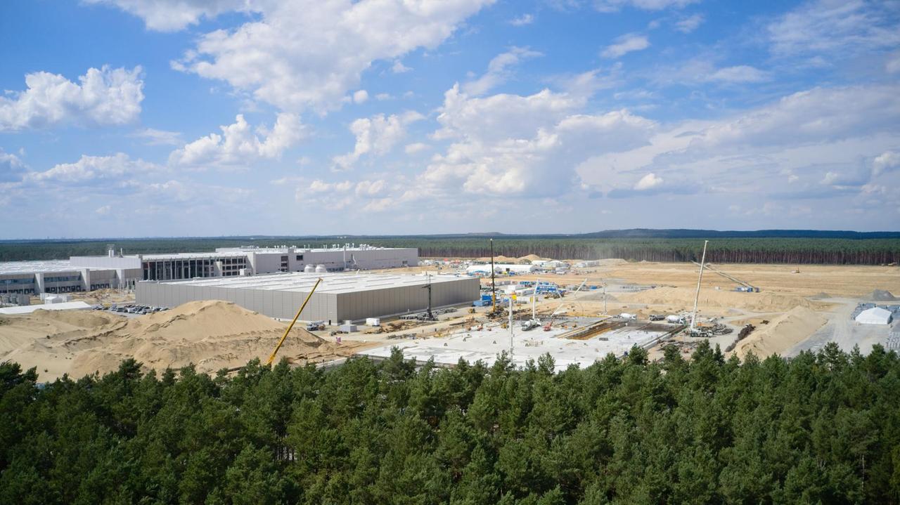 Blick auf die Tesla-Baustelle in Grünheide in Berlin, im Vordergrund Wald, im Hintergrund der Betonbau der Gigafactory. Blick auf die Tesla-Baustelle in Grünheide in Berlin, im Vordergrund Wald, im Hintergrund der Betonbau der Gigafactory.