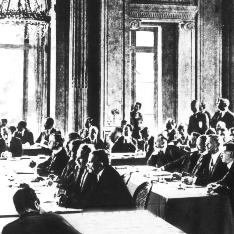 Die Sitzung vom 7. Mai 1919, in der der Vertragstext der deutschen Delegation zugestellt wurde. Der Versailler Vertrag war der wichtigste der Pariser Vorortverträge, die 1919/20 den 1. Weltkrieg beendeten. Der Versailler Vertrag wurde am 28.6.1919 im Versailler Schloß zwischen Deutschland und 27 alliierten und assoziierten Mächten unterzeichnet und trat am 20.1.1920 in Kraft. Ohne deutsche Beteiligung wurde ab dem 18.1.1919 in Paris der Text des Friedensvertrages zwischen Wilson, Lloyd George, Clemenceau und Orlando (Die "Großen Vier") ausgearbeitet. Am 7.5.1919 wurde der Text der Deutschen Delegation zugestellt 